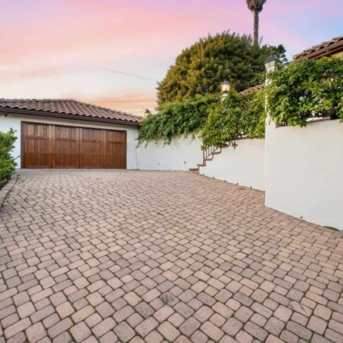 a driveway with brick pavers, and a garage in the background