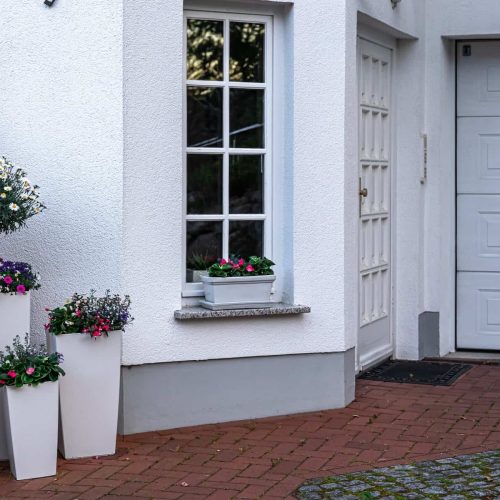Part of the exterior of the house with white color with flowers.